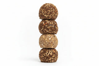 Stack of four round, brown energy balls for birds on a white background