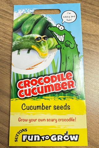 Packaging for cucumber seeds with cartoon crocodile design on a wooden surface