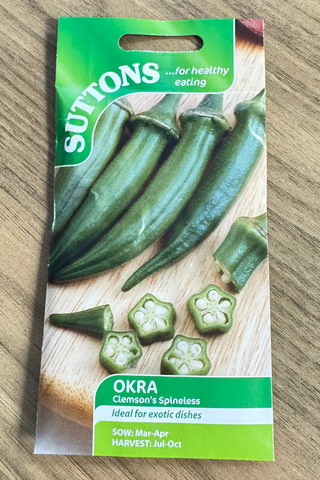 Suttons okra seed packet on a wooden surface