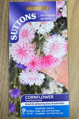 Suttons cornflower seed packet with pink and white flowers on a wooden surface