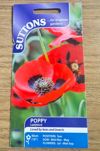 Suttons poppy seed packet on a wooden surface