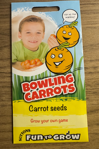 Packaging of Bowling Carrots carrot seeds with a child and carrots illustration on a wooden surface