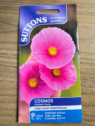 Suttons cosmos seed packet with pink flowers on a wooden surface