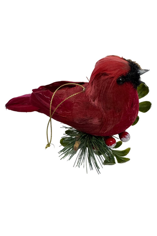 Red cardinal bird ornament with greenery and berries on a white background