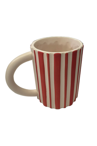 A ceramic mug with red and white stripes design, placed on a table.