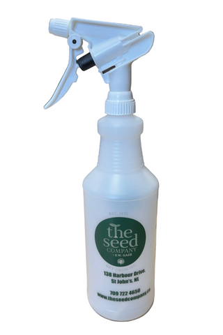 A white spray bottle with a green label that has 'The Seed Company' branding, displayed on a countertop in a store.