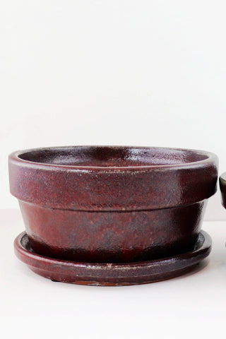 Two brown ceramic pots with saucers on a white background