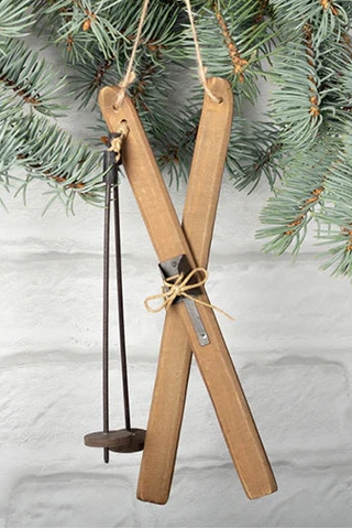 Wooden ski ornament hanging on a branch with a snowy background